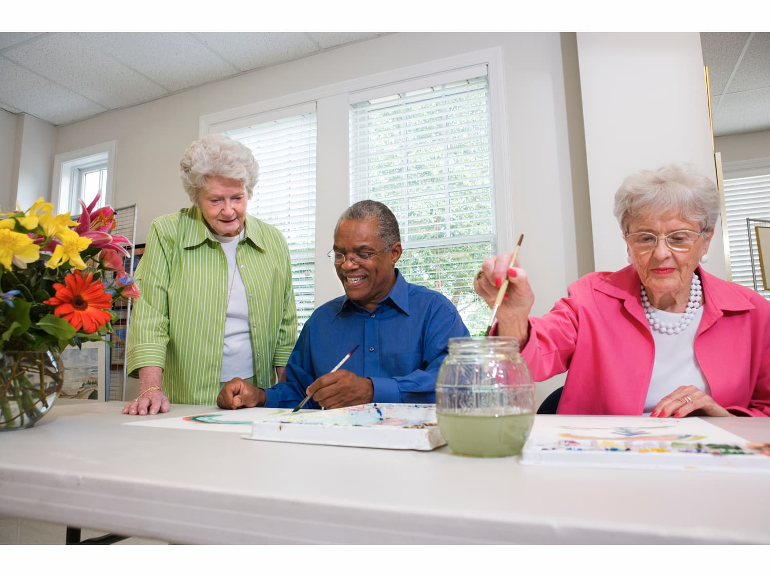 attività per anziani in casa di riposo: la pittura. un anziano al centro e due anziane ai lati 