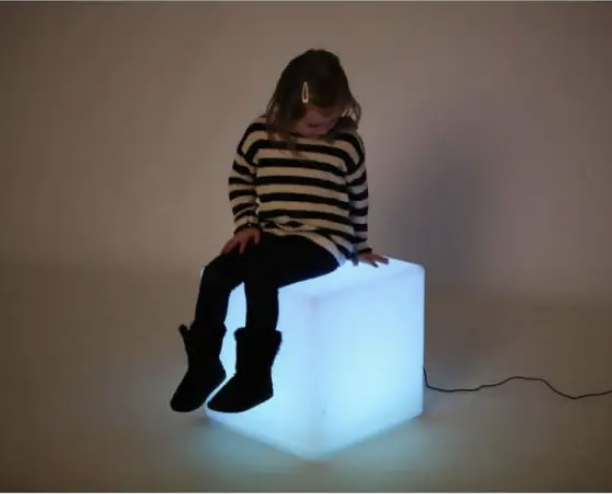 Metodo snoezelen: bambina seduta su un cubo luminoso