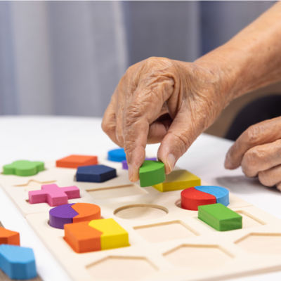 mano di un anziano che gioca con formine colorate ad incastro per allenare la multisensorialità