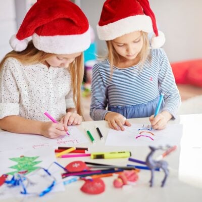 Due bambine con il cappello di natale che fanno lavoretti di Natale