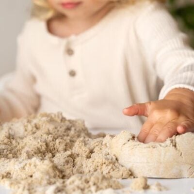 bambina che gioca con sabbia cinetica su un tavolo