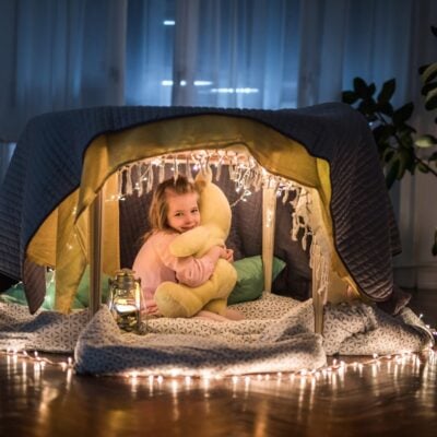 bambina al di sotto di una coperta colorata e illuminata
