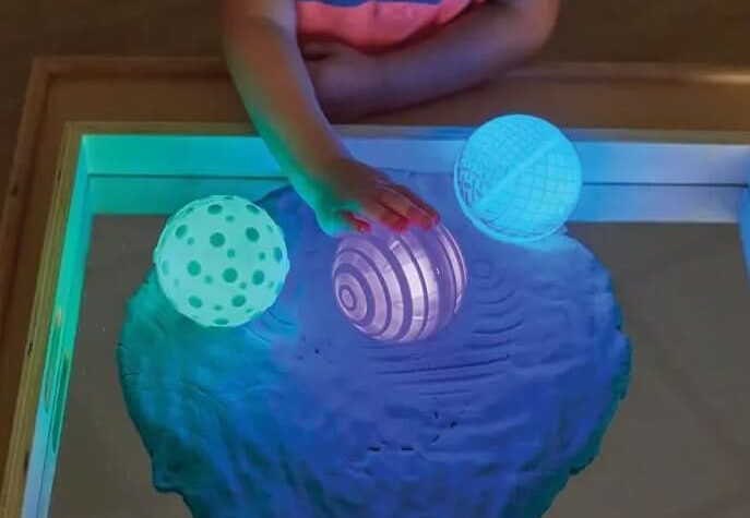bambino/a che gioca con palline luminose sensoriali