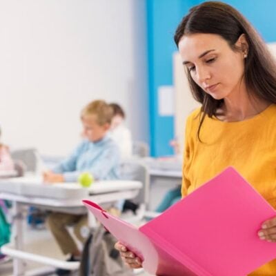 docente che legge. Sullo sfondo la classe