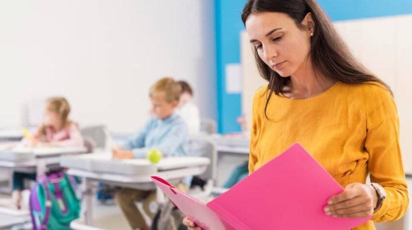 docente che legge. Sullo sfondo la classe