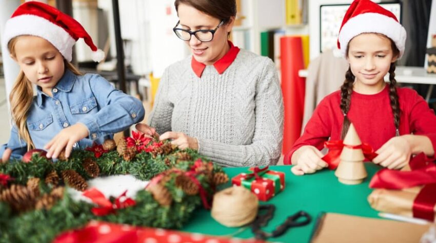 insegnante con due allievi a lato. Creano lavori di natale