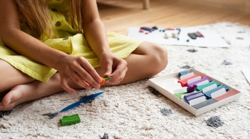 bambina che gioca con carta e colori sul pavimento