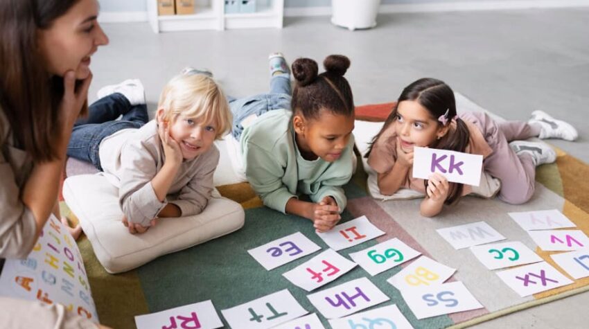 bambini che giocano con fogli ritraenti lettere in inglese